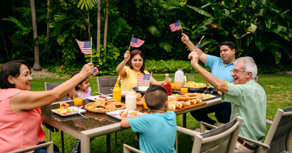 new york family holding up american flags on outside patio while eating a meal