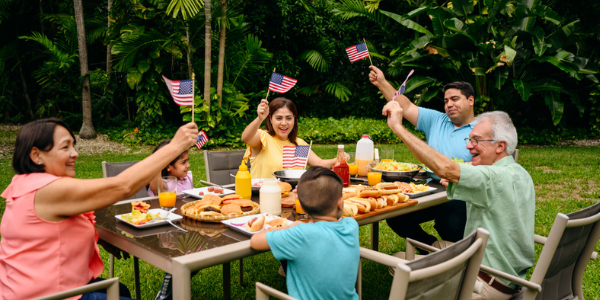 new york family holding up american flags on outside patio while eating a meal
